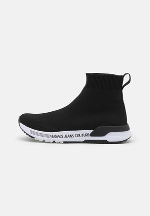 Schwarzer Strick-Sneaker im Sockenstil mit hohem Knöchel, weißer Sohle und kontrastierenden Logodetails an der Seite. Glatte Textur und stromlinienförmiges Design.