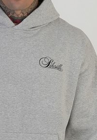 Hanorac gri cu textură moale, având sigla "SikSilk" în scris cursiv negru pe partea superioară stângă a pieptului. Design clasic cu glugă.
