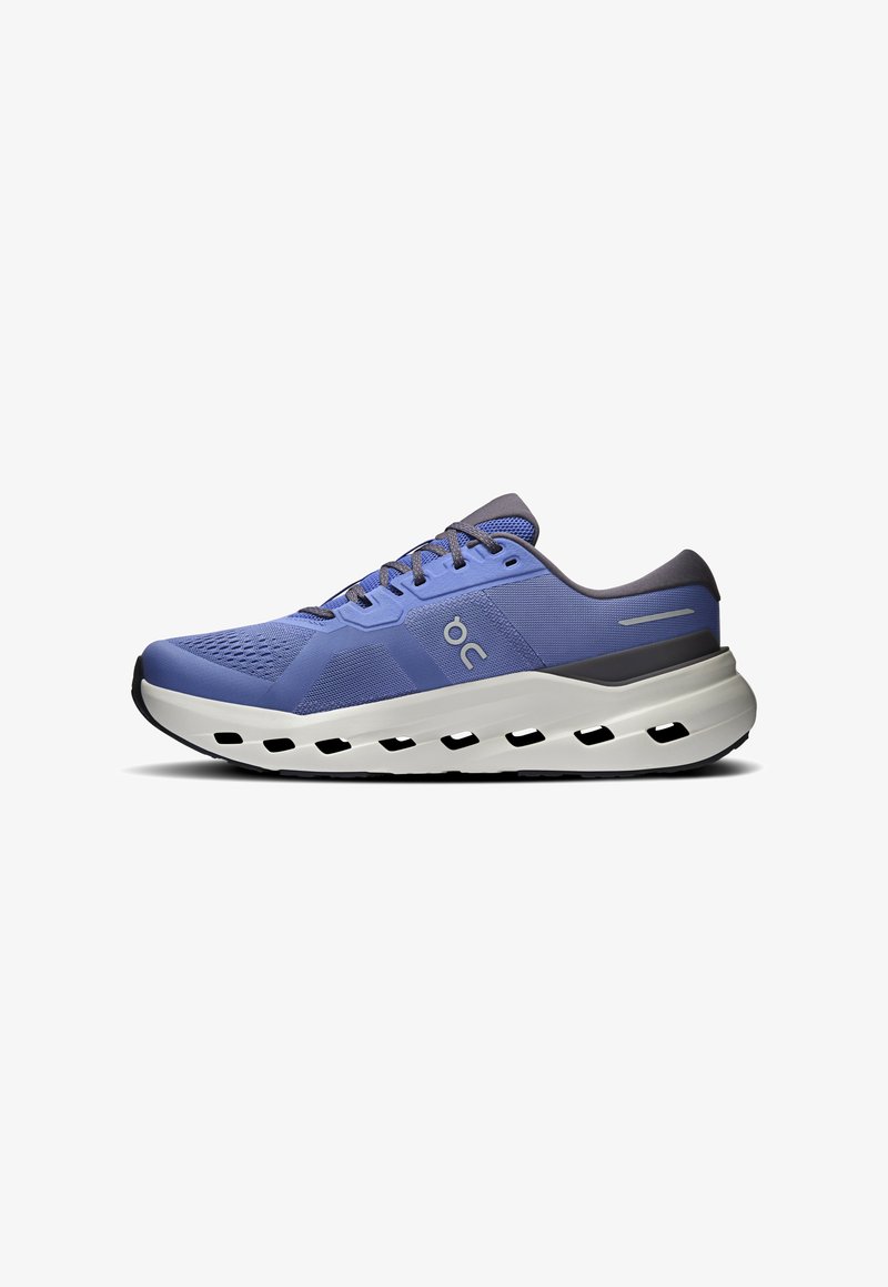 Chaussure de course athlétique bleue avec des lacets gris, un mesh respirant et une semelle blanche épaisse amortie avec des trous de ventilation.