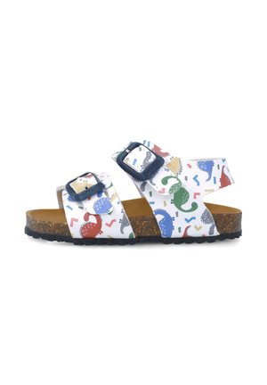 Sandalias blancas con patrones de dinosaurios multicolores, dos correas ajustables, plantilla de corcho y suela texturizada negra.