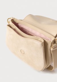 Beige leren en suède crossbodytas met afneembare band, voorvak en roze stoffen binnenvoering zichtbaar.