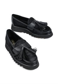 Czarne półbuty na koturnie, wykonane z zamszu i skóry, z akcentem w postaci frędzli oraz teksturowaną podeszwą.