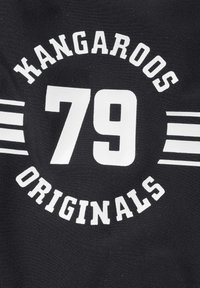 Schwarzer Stoff mit großen weißen Texten, die "KANGAROOS ORIGINALS" und "79" lesen, umgeben von einem kreisförmigen Design und zwei weißen Streifen.