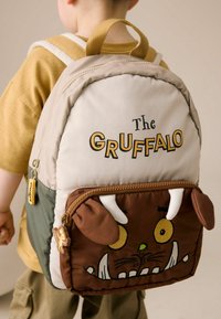 Barnens ryggsäck med en beige och brun färgkombination, mjuk Gruffalo-karaktärsdesign, dragkedjeficka och hållbara remmar.