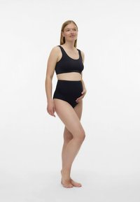 Črn športni modrček iz bombaža in komplet hlačk z visokim pasom. Brezšivna zasnova, mehka tekstura in raztegljiv material. Minimalističen slog brez vidnih logotipov.