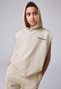 Felpa beige senza maniche con cappuccio ampio, con la scritta "ALLSAINTS" in nero sul davanti, realizzata in morbido tessuto di cotone.