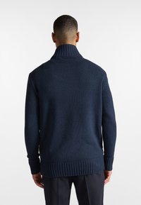 Maglione in maglia blu navy con colletto alto e polsini e orlo a coste. Presenta un motivo testurizzato e una vestibilità rilassata, visto da dietro.
