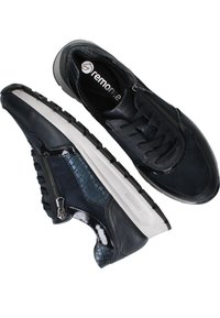 Marineblaue Sneakers aus einer Kombination aus glatten und strukturierten Materialien, mit Reißverschluss und einer kontrastierenden weißen Gummisohle mit Rutschfestigkeit.