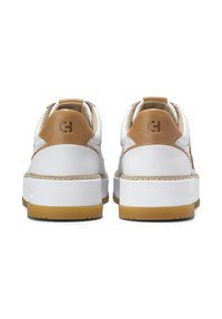 Par de zapatillas blancas con acentos en piel marrón en el talón, suelas gruesas blancas y un logo grabado en las lengüetas traseras del talón.