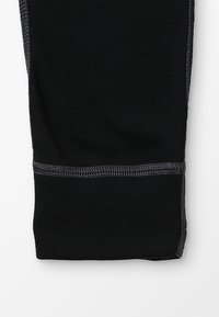 Leggings sportivi neri con una texture a coste e cuciture grigie a contrasto ai polsini, caratterizzati da un design aderente e materiale elasticizzato.