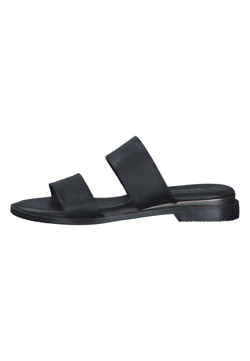 Sandale à glissière en cuir noir avec une semelle plate, deux larges brides traversant le pied, et un design minimaliste. Semelle extérieure en caoutchouc durable.