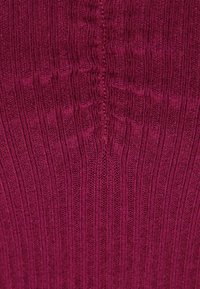Bordeauxfarbener, gerippter Strickstoff mit vertikalen Linien und einer strukturierten Oberfläche; verfügt über eine zentrale Naht, die vertikal in der Mitte verläuft.
