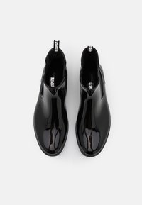 Bottines noires patinées avec une finition élégante, panneaux latéraux élastiques et tirettes pour un enfilage facile. Doublure intérieure en tissu texturé.