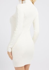 Robe blanche côtelée avec un col montant, une silhouette ajustée et des détails lacés sur les manches. Texture lisse avec une légère brillance.