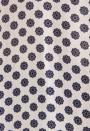 Tessuto bianco con un motivo ripetuto di piccole forme floreali blu scuro disposte in file diagonali.