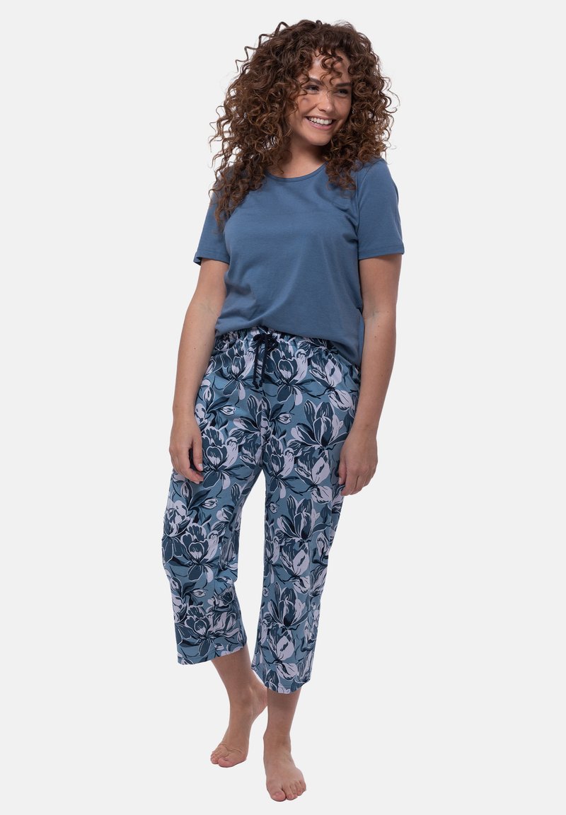 Blaues Baumwoll-T-Shirt kombiniert mit gemusterten Caprihosen mit floralem Design in Blau und Weiß. Die Hose hat einen elastischen Bund mit Kordelzug.