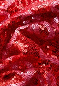 Tessuto rosso con paillettes, dalla superficie lucida e strutturata, caratterizzato da paillettes circolari sovrapposte disposte in motivi ondulati.