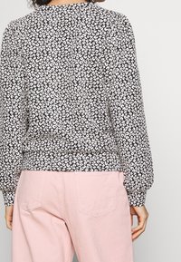 Felpa a righe bianche e nere con una finitura testurizzata, scollatura rotonda e orlo elasticizzato, abbinata a pantaloni rosa chiaro.