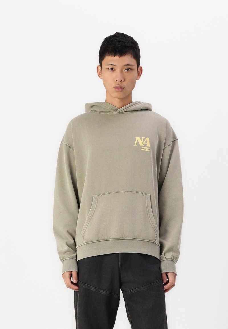 Olivengrønn hettegenser laget av bomull, med kengurulomme og ribbestrikkede mansjetter. Inkluderer en gul grafikk på venstre bryst.