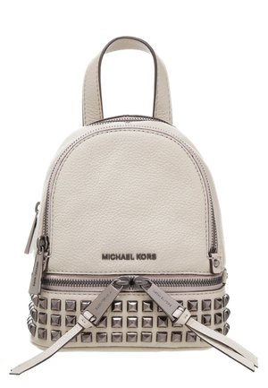 Petit sac à dos en cuir beige Michael Kors avec tirettes de fermeture éclair argentées et clous carrés en métal sur le bas devant.