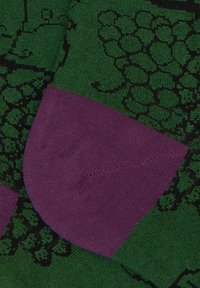 Gestrickter Socken mit dunkelgrüner Basis und einem Traubenmuster, betont durch Fersen- und Zehenbereich in einfarbigem Lila, aus weichem Stoff gefertigt.