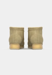 Tan suede ankle boots with a rounded toe, short shaft, and a low, solid heel. Seams are visible along the sides and back.