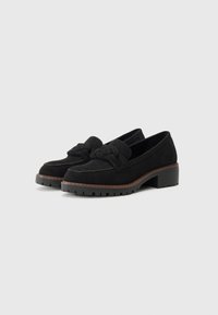 Mocasines de ante negro con un detalle de nudo en la punta, tacón apilado y suela de goma texturizada. Diseño limpio con acabados suaves.