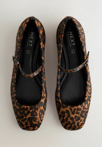 Leopard print flats with a black leather sole, square toe, and a thin adjustable strap across the instep. Soft fur-like texture.