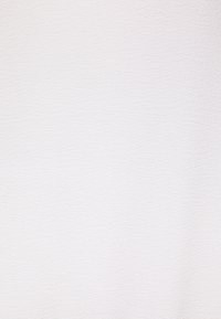 Vitt texturerat tyg med ett subtilt, fint mönster som har en något upphöjd yta som tillför djup och visuell intresse.