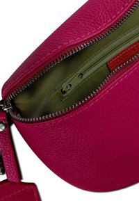 Roze leren tas met een gestructureerd oppervlak en een zilveren rits. Het interieur heeft een olijfgroen voering en een klein rood ritscompartiment.