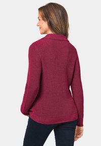 Strickpullover in Burgunderrot mit umschlagbarem Kragen, gerippter Textur und langen Ärmeln. Figurbetonter Schnitt mit leicht ausgestellt geschnittenem Saum hinten.