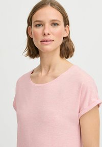 T-shirt rosa chiaro a maniche corte con scollatura rotonda. Realizzato in tessuto morbido e leggero con una vestibilità comoda e maniche arrotolate.