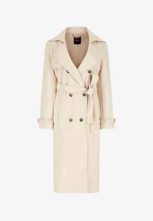 Trench-coat beige à double boutonnage avec larges revers, ceinture nouée à la taille, poignets boutonnés et détail de chaîne dorée à l'intérieur du col.