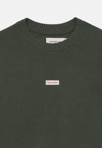 Felpa verde scuro con colletto a costine e polsi. Presenta un piccolo patch logo bianco e rosso sul petto. Materiale in cotone con finitura texturizzata.