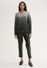 Grau-schwarz ombre Strickpullover mit langen Ärmeln, kombiniert mit schwarzen Kunstlederhosen und schwarzen Loafers. Eleganter, texturierter Look.