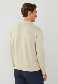 Beige Baumwollpullover mit langen Ärmeln, gerippten Bündchen und Saum sowie einem klassischen Kragen. Verfügt über eine einfache, glatte Textur und keine sichtbaren Muster.