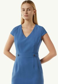 Blaues, eng anliegendes Kleid mit V-Ausschnitt, kurzen Ärmeln und Knöpfen an der Taille. Maßgeschneidertes Design mit vertikalen Nähten für einen strukturierten Look.