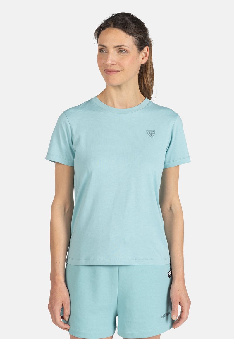 Světle modré tričko s kulatým výstřihem z měkké látky, krátkými rukávy, s malým logem na hrudi a pohodlným střihem, v kombinaci s odpovídajícími šortkami.