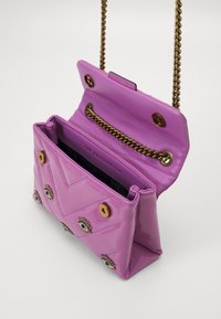 Rosa lackläder väska med guldkedja, prydd med ögonmotiv och ett chevronmönster. Insidan är fodrad i svart.