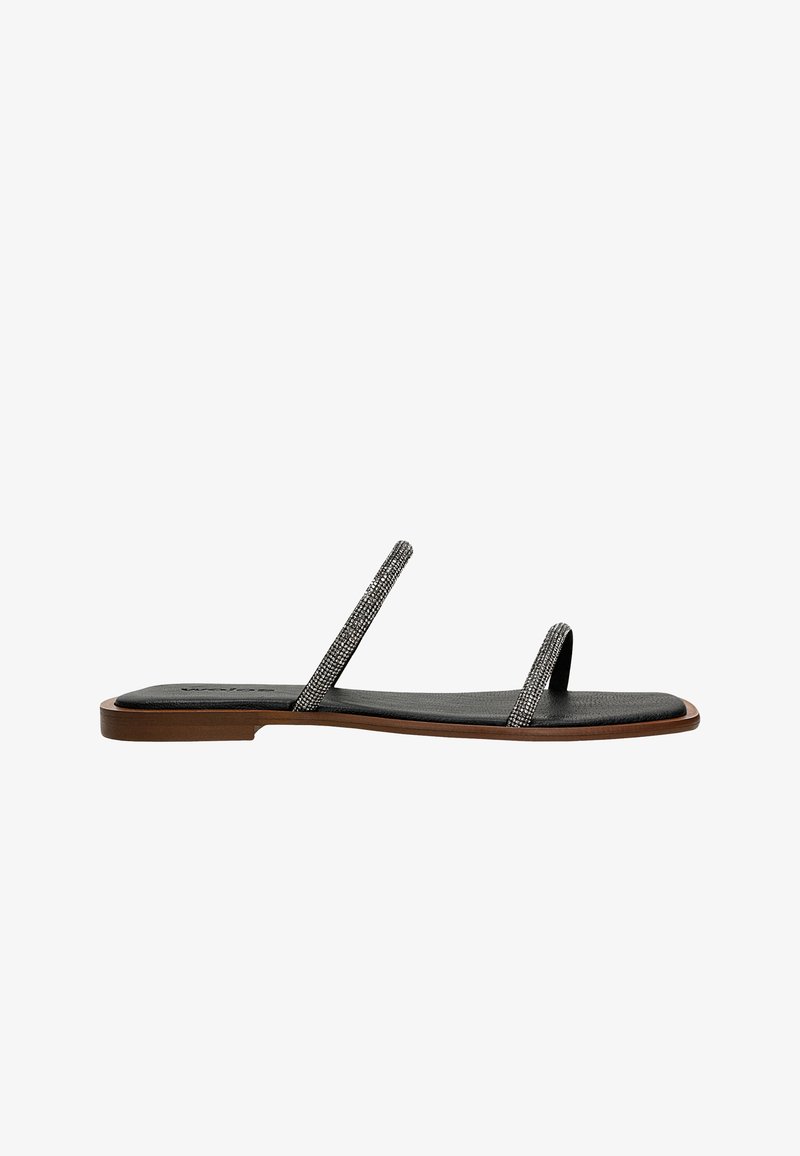 Zwarte leren platte sandalen met dunne banden met decoratieve metalen accenten en een gestructureerde binnenzool; minimalistisch ontwerp met een platte zool.