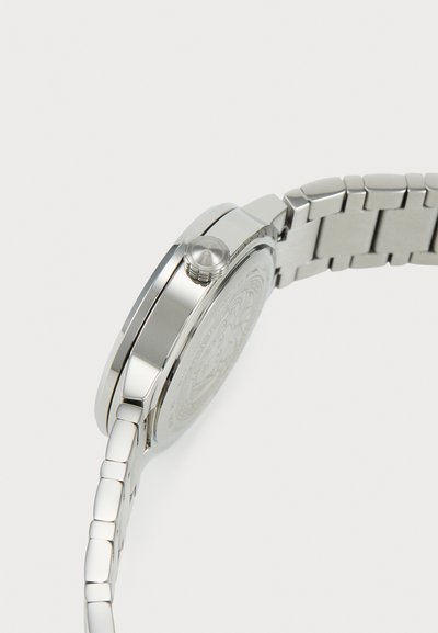 Ασημένιο ρολόι από ανοξείδωτο ατσάλι με στρογγυλή κάσα, γυαλιστερή επιφάνεια, υφασμένη πλάτη και μπρασελέ με σύνδεσμο και κλείσιμο αναδίπλωσης.