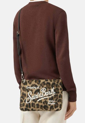 Tas met luipaardprint en witte tekst, voorzien van een ritssluiting en verstelbare zwarte band, gedragen over de schouder tegen een bruine trui.