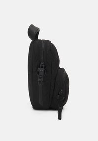 Sort puffer taske med en rund form, dobbel lynlås og et læderhåndtag på toppen. Ydersiden har en glat, quilted tekstur.