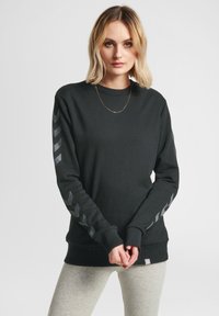 Sudadera negra de manga larga con acentos en forma de chevron gris. Fabricada con tejido suave, tiene un cuello redondo y puños acanalados.