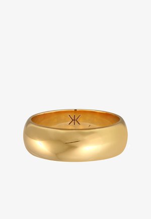 Guldtonet metalring med en glat, rund form. Indeni har den et enkelt, præget symbol. Reflekterende overflade med en poleret finish.