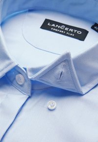 Jasnoniebieska, w paski koszula z guzikami przy kołnierzyku. Cechy to białe guziki oraz metka z napisem "LANCERTO COMFORT PLUS."