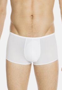 Boxer da uomo bianchi realizzati in tessuto trasparente. Presentano un design aderente, una vita elasticizzata e una cucitura centrale per dare struttura.