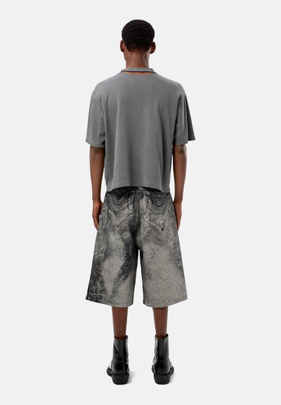 Gray cropped t-shirt with short sleeves paired with distressed, knee-length denim shorts featuring a faded wash and pocket accents. Black boots worn.