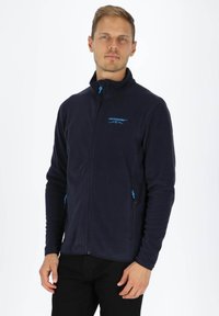 Marineblaue Fleecejacke mit hohem Kragen, frontalem Reißverschluss und blauen Akzenten; zwei Reißverschlusstaschen auf der Vorderseite; weiche Textur.