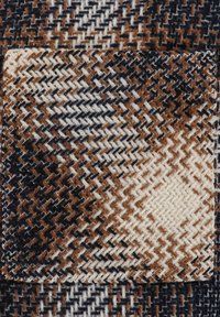 Vævet stof med et houndstooth-mønster i brune, sorte og hvide farver. Teksturområde med diamantformer og kontrasterende tråde.